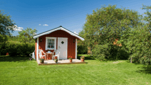 A small red granny flat house on a grassy lawn