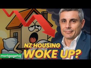 A man smiling with text underneath him "NZ housing woke up?". There is a yellow cartoon house behind him with a face mid yawn